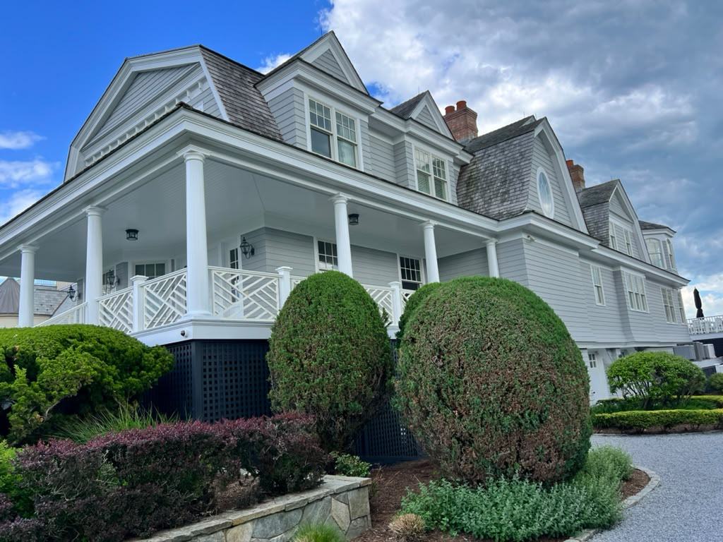 Shingle-style home with wraparound porch, freshly painted gray siding and white trim