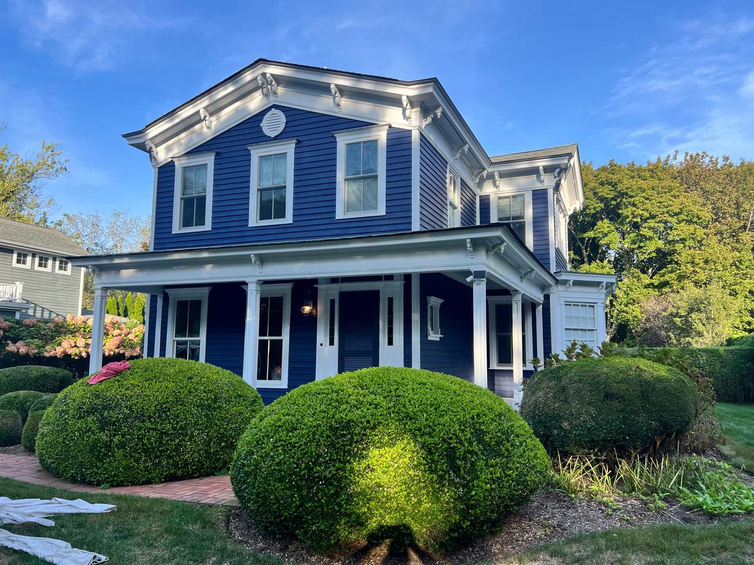 Blue colonial house with white trim after exterior painting